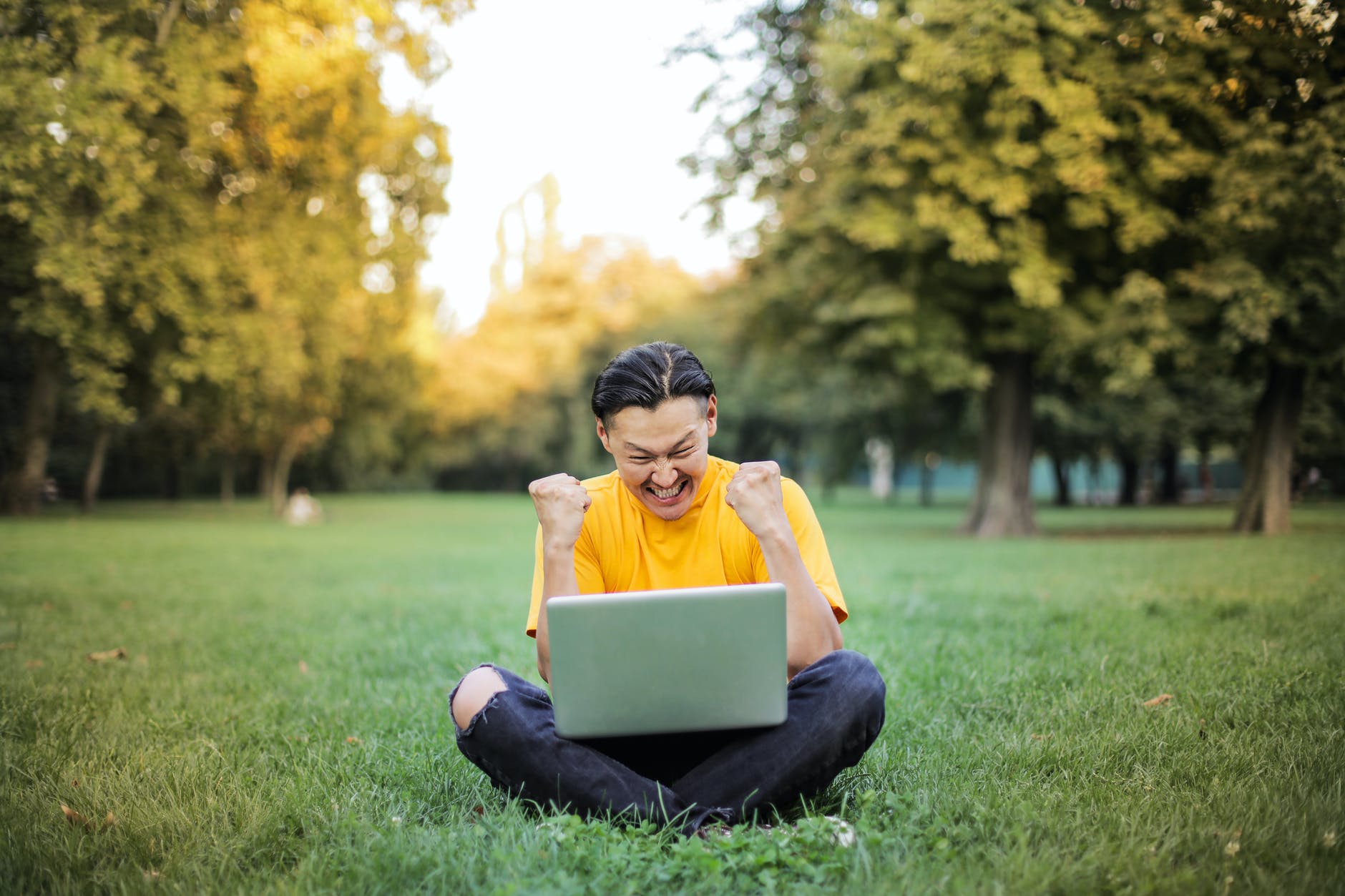 Image Description:
a young masculine presenting person sitting on a green grass field with a laptop and both arms raised, and fists clenched excitedly with superimposed text reading, “Referencing with Mendeley in 8 Steps”. 
End of Image Description